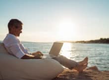 man relaxing with his laptop at the beach