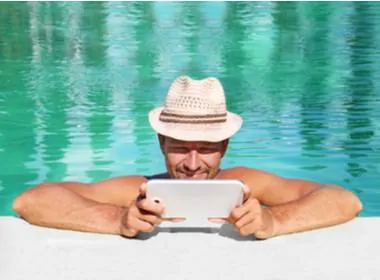 guy with a hat in the pool playing at Springbok Casino on his tablet