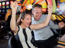 a young couple excitedly cheering the result of a casino game they are playing at a terminal