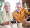 older white haired couple smiling as they playa casual game on the sofa