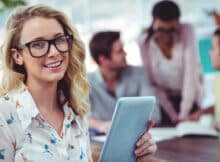 a woman in her early 30's working on a team of creators. she is looking at the camera and smiling.