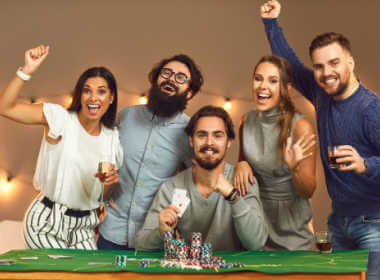 lima orang dewasa muda, tiga pria dan dua wanita, dengan gembira merayakan kemenangan lainnya di blackjack