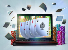 laptop computer screen showing four aces with cards floating all round and poker chips stacked on the table