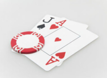 the ace of hearts and jack of spades representing a blackjack. A red chip sits on the corner of the two cards