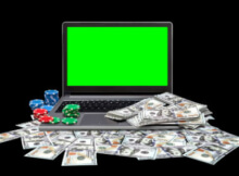 a laptop casino on a table with coins and USD on the keyboard showing that US gamers can play casino games online
