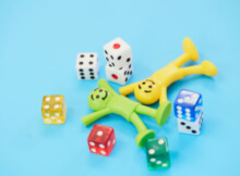 toys man and woman smiling and lying on floor with colored dice around them taking a break from playing online casino games.
