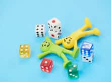 toys man and woman smiling and lying on floor with colored dice around them taking a break from playing online casino games.