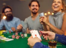 two bearded men and a woman playing Texas Hold'em. A fourth person is shown holding a pair of aces.