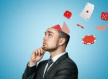 young man in a business suit and tie thinking about his next decision in blackjack as chips and cards come out of his head