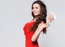 attractive brunet woman in red dress showing the "money" she received as a bonus from an online casino