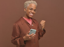 happy senior African-American woman with short white hair winning with her smartphone