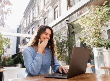 young woman with blue long sleeve knitted top playing on laptop casino outdoors on pleasant day not hot or cold