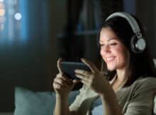 Woman sitting on the sofa playing on her phone wearing headphones