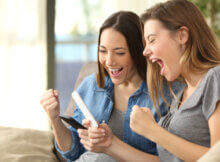 Two twenty-something women celebrating a win playing an online casino on their phones