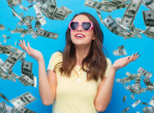 attractive young woman in pink heart-shaped glasses ecstatic over winning big jackpot as dollars rain all around her
