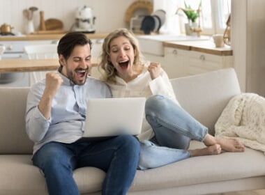 young couple gaming on their sofa at an online casino celebrating a win