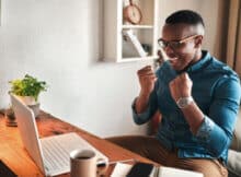 thirtyish black male excited over gaming results at an online casino. He is playing on his laptop computer.