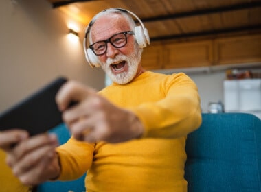 happy older gamer guy playing on his phone with earphones on