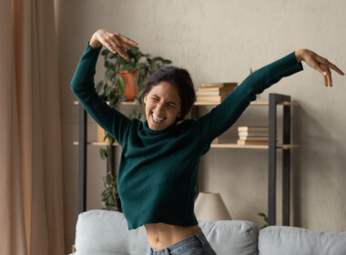 young woman on her sofa showing unbridled joy