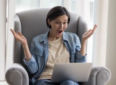 fifty-something woman sitting comfortably on a soft chair at home happy after winning a game at an online casino