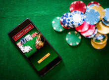 a smartphone on a green felt background with casino online on the face and casino chips of many colors on the felt