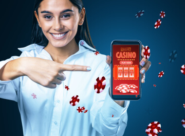 a smiling young woman holding a smartphone with online casino on the face and chips all around it