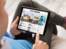 a man sitting on his sofa reading the news on his tablet
