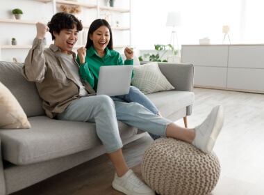 young Asian couple enjoying an online casino game while sitting comfortably on the sofa