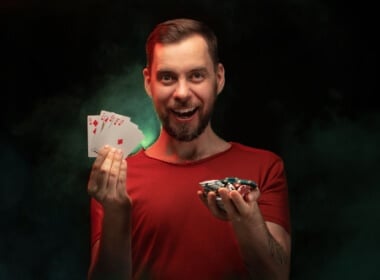 Young man smiling holding chips and a royal flush