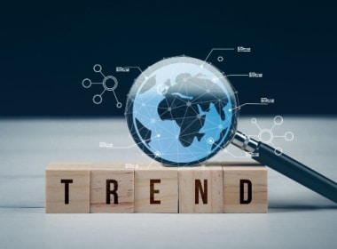 a magnifying glass magnifying the world as if from outer space and five blocks spelling trend