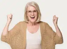 A very happy middle-aged woman with long blond hair smiling toward the camera